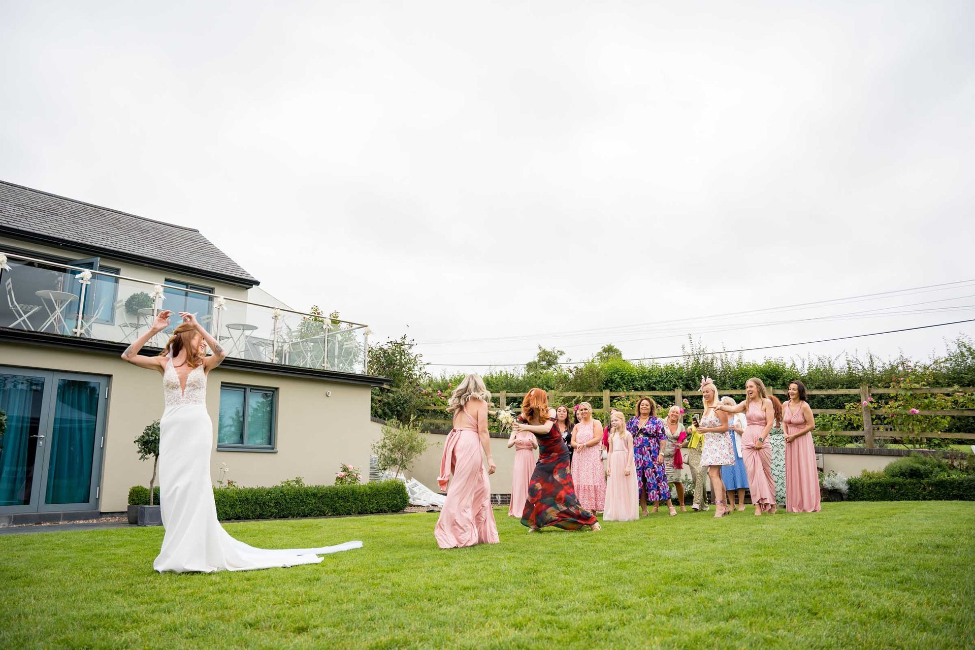 A bride and her bridesmaids are throwing a bouquet of flowers in a field.