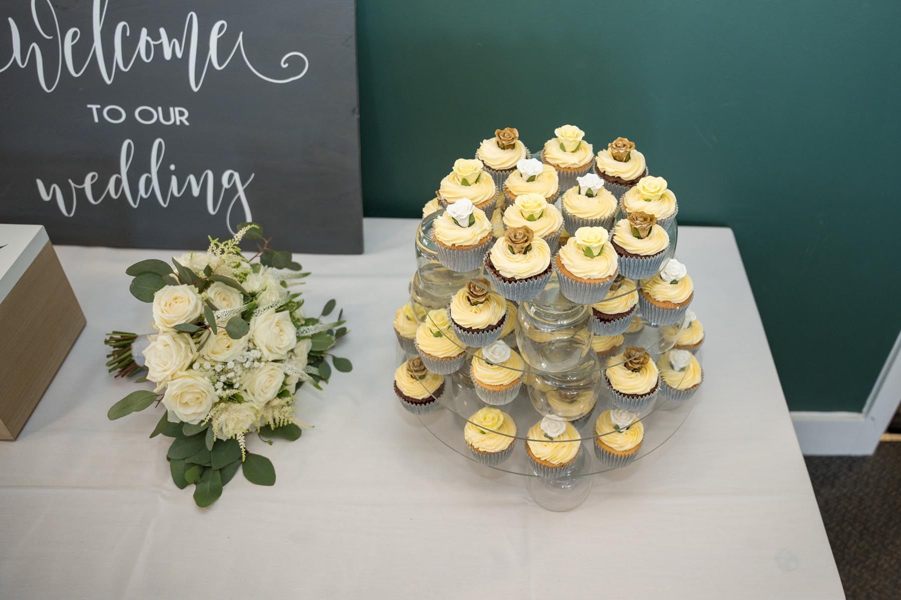 A table with a bouquet of flowers and cupcakes on it.