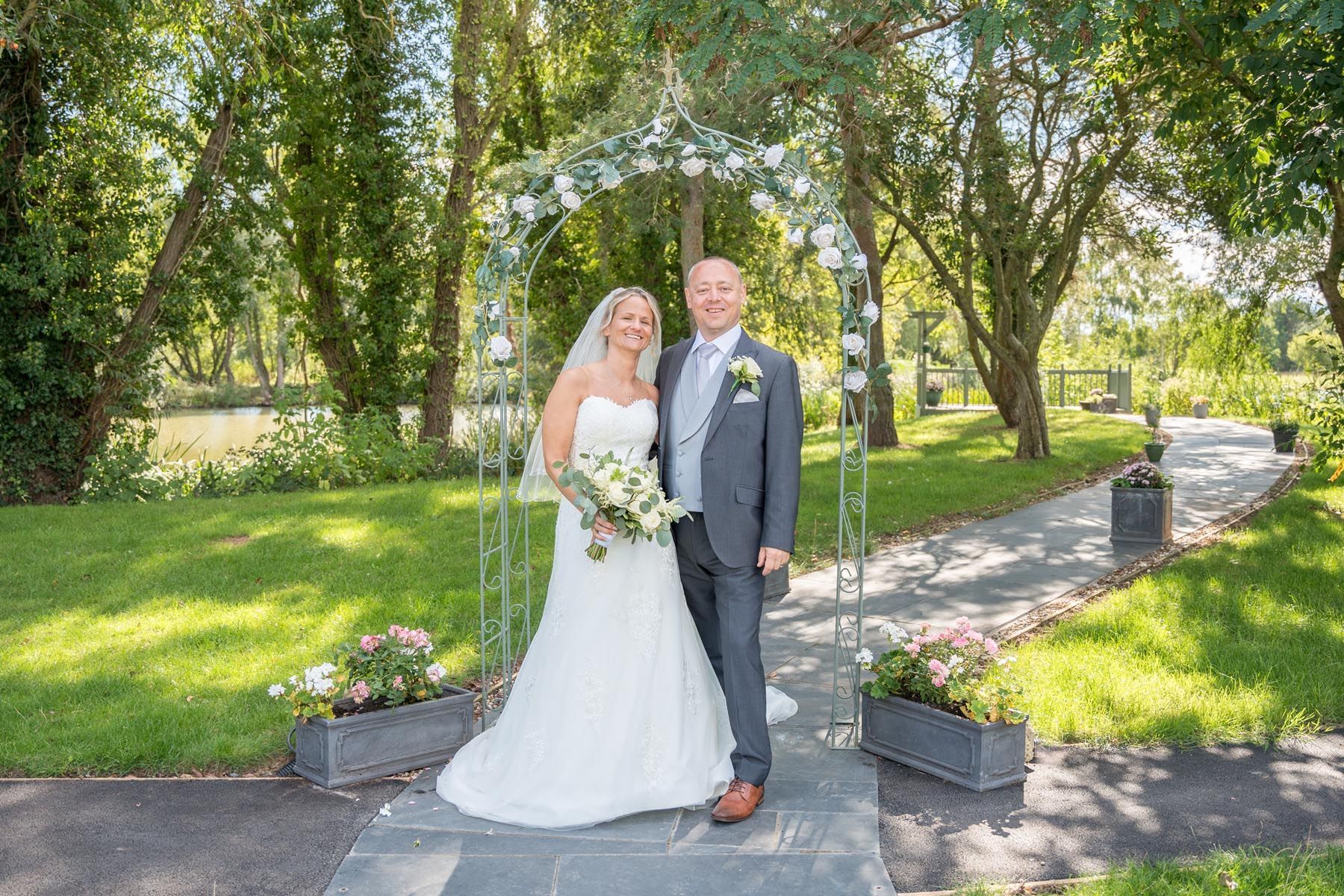 A bride and groom are posing for a picture in a park.