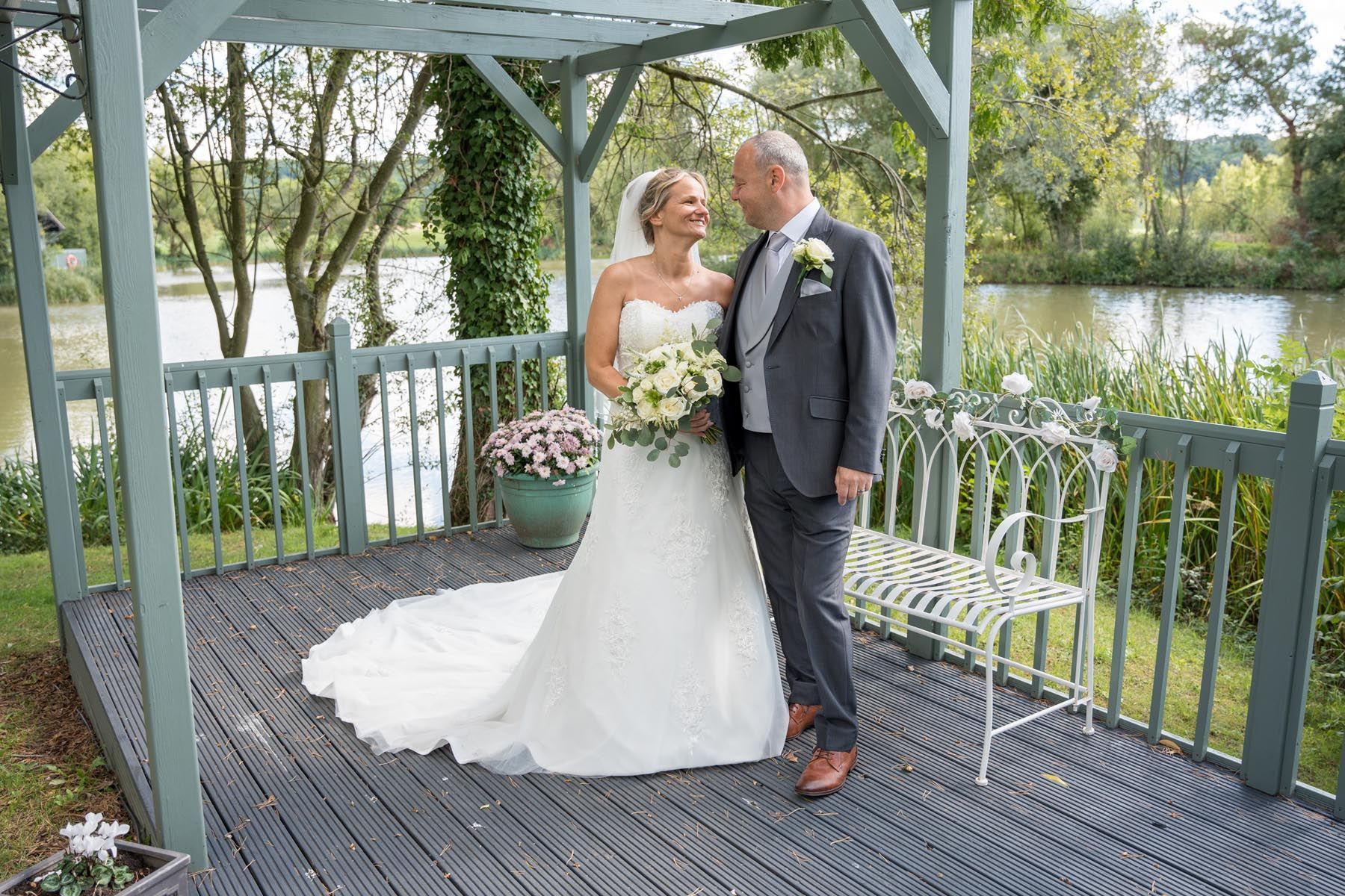 A bride and groom are posing for a picture under a gazebo.