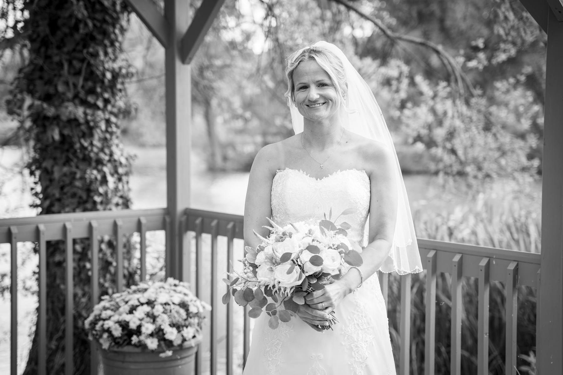 A black and white photo of a bride in a wedding dress holding a bouquet of flowers.