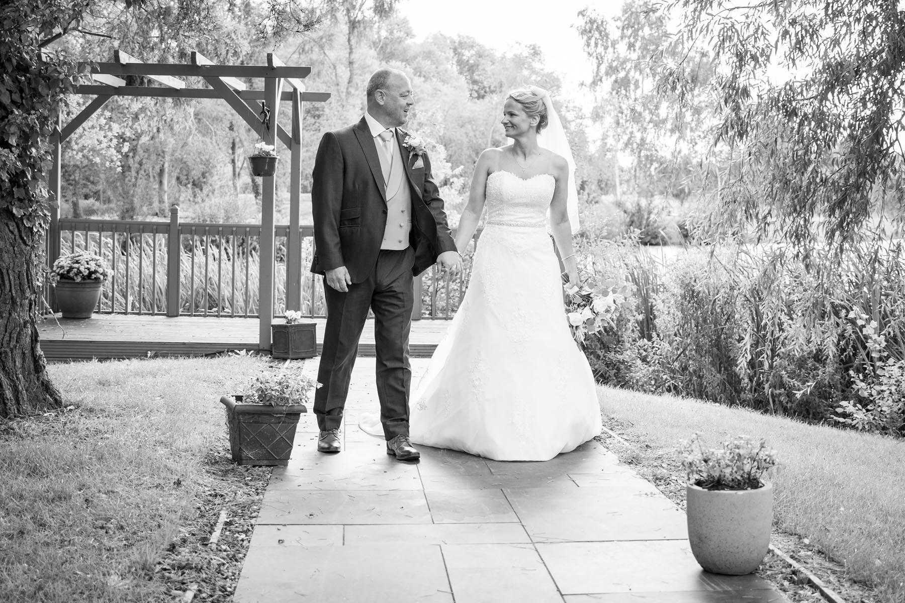 A black and white photo of a bride and groom holding hands.