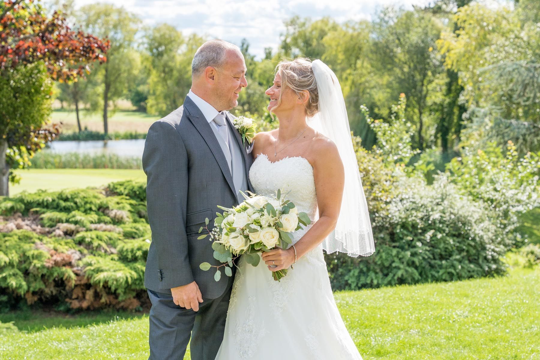 A bride and groom are posing for a picture in a park.