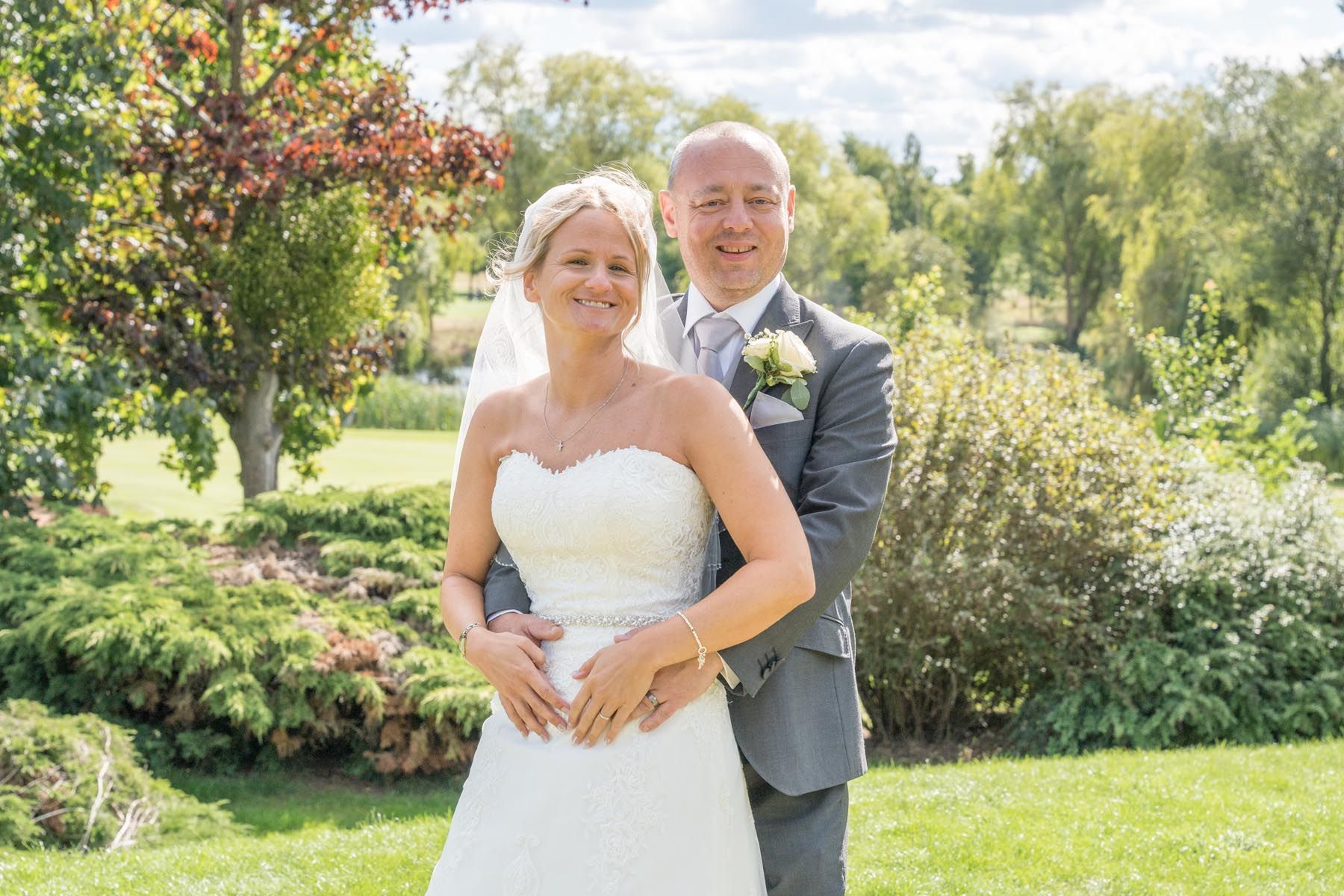 A bride and groom are posing for a picture in a park.