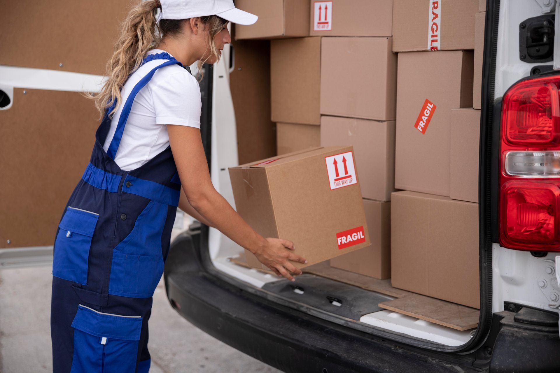 Delivery worker loading cardboard boxes into the back of a van