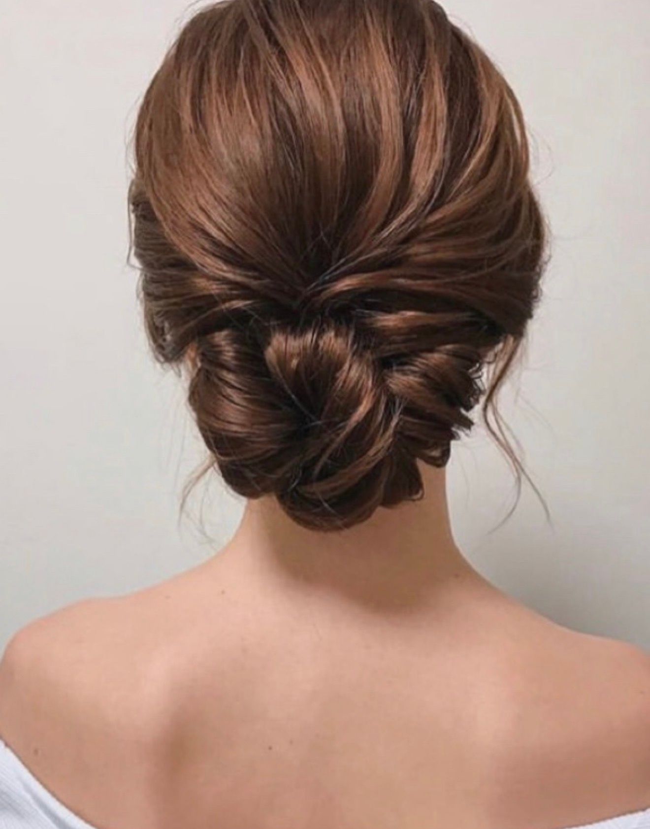 Back view of an elegant brown updo hairstyle on a bare-shouldered person
