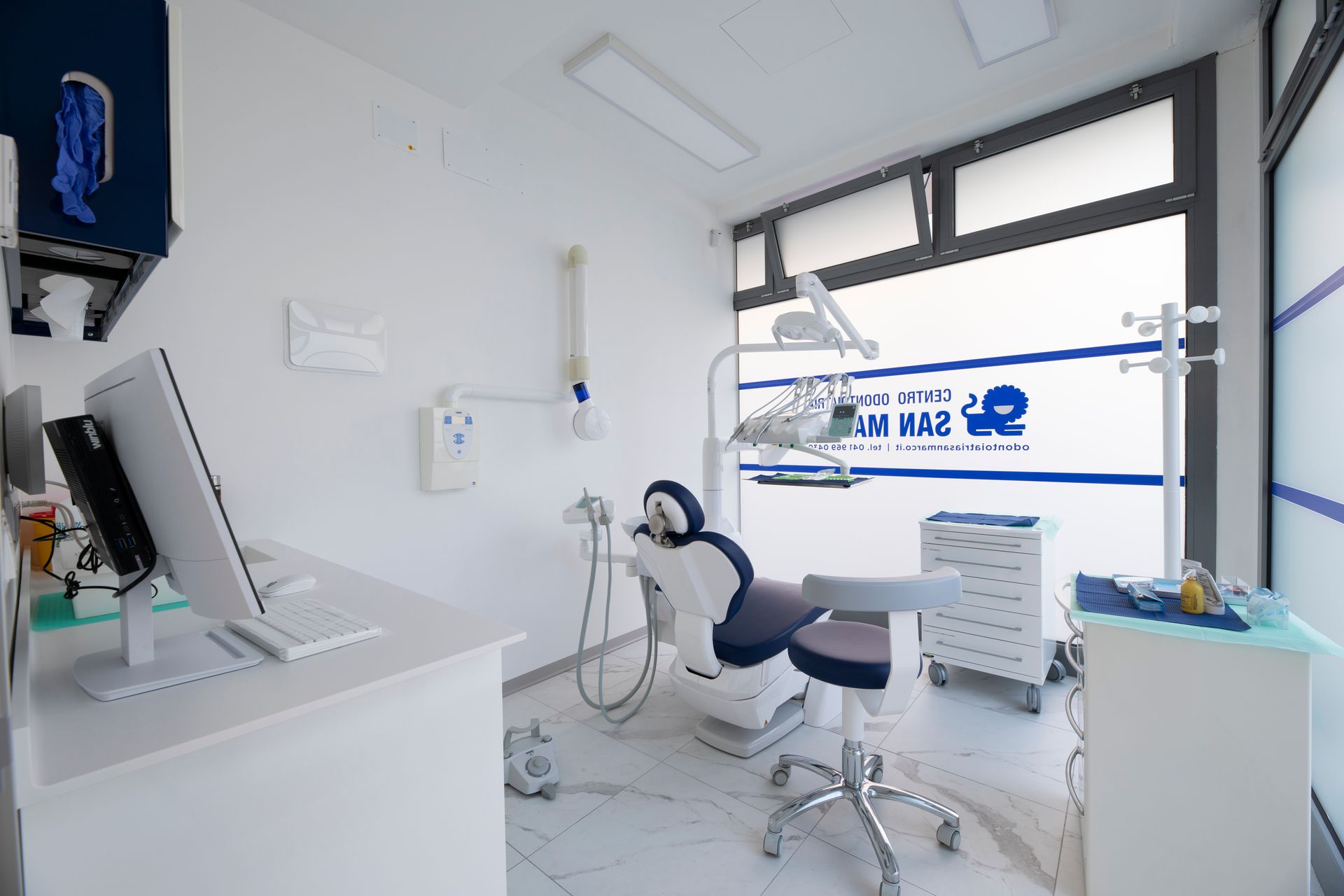 Sala visite odontoiatriche con poltrona odontoiatrica, attrezzatura e computer.