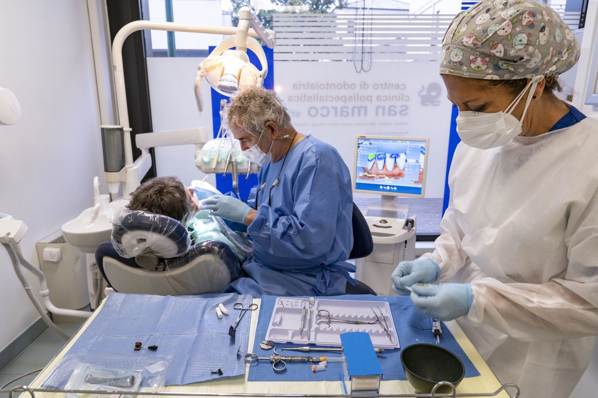 Dentista e assistente in studio dentistico visitano un paziente. Attrezzature e strumenti sono sul tavolo.