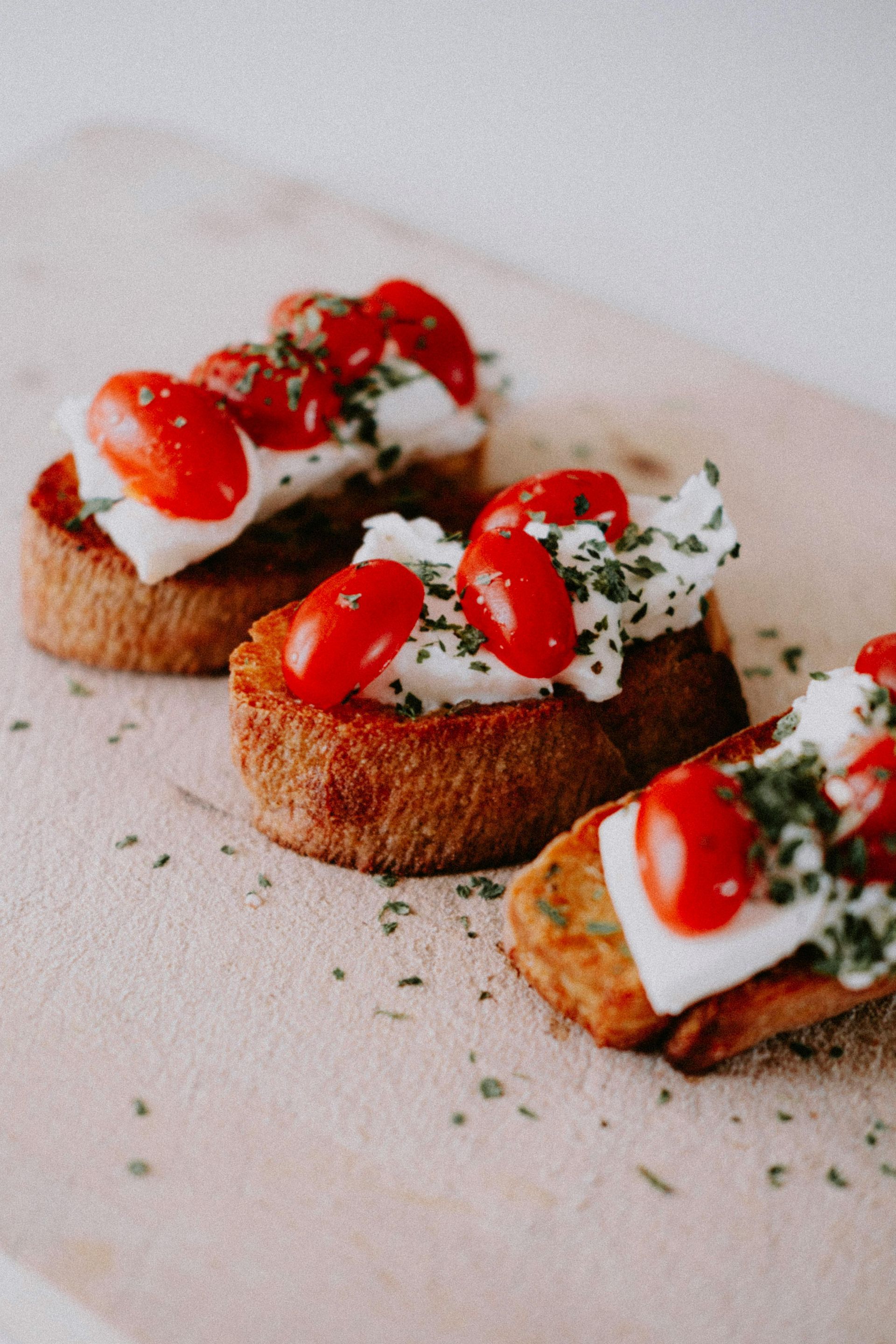A close up of three sandwiches with tomatoes and cheese on a plate.