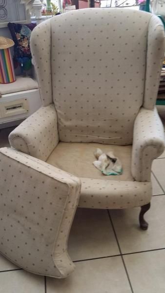 Upholstered beige armchair with matching footrest on tiled floor, in a room with window light