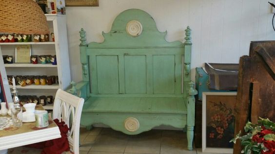 Mint-green painted bench displayed in a shop, flanked by shelves and framed art.
