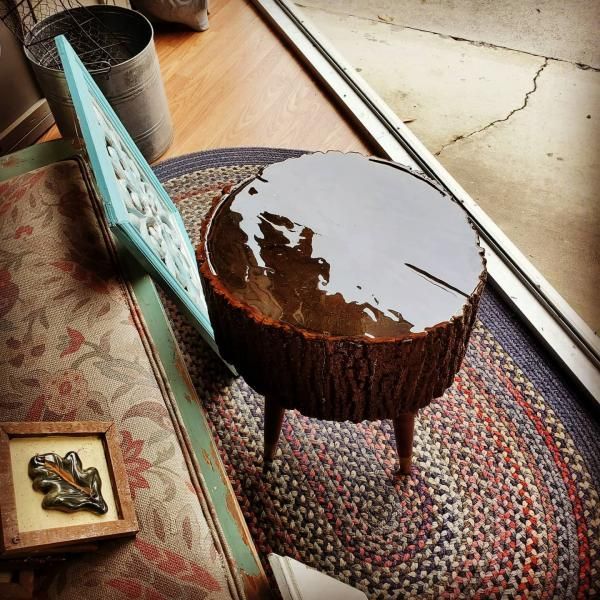 Small round wooden side table with a glossy top on a patterned rug by a sunlit window
