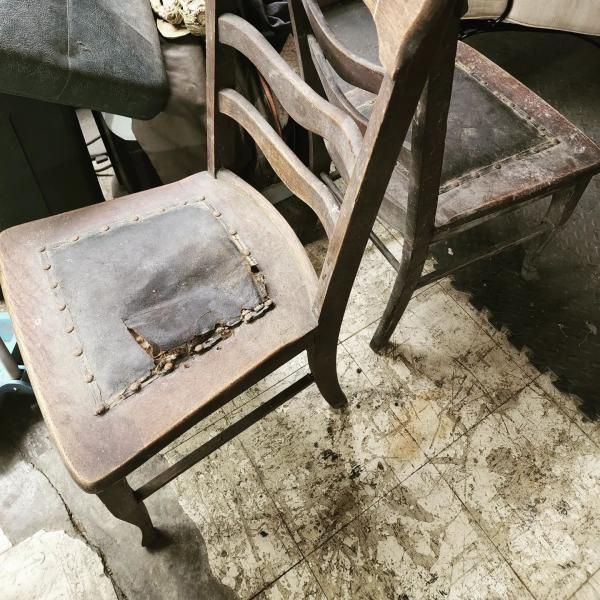 Old wooden chair with a torn cushion in a dusty, worn room