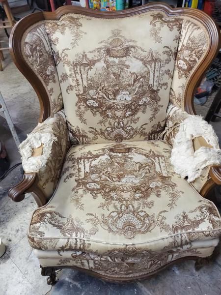 Vintage upholstered armchair with ornate beige floral fabric and carved wooden frame