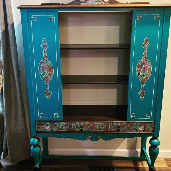 Turquoise vintage cabinet with open shelves, floral painted doors, and carved legs