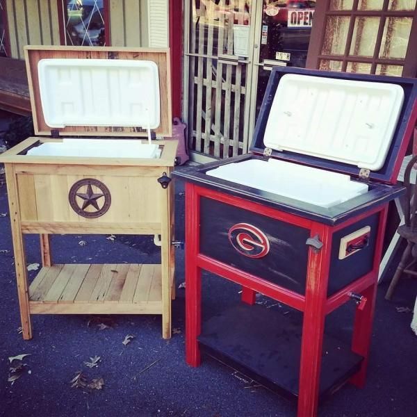 Two open chest freezers on stands, one tan and one red, displayed outside a store.