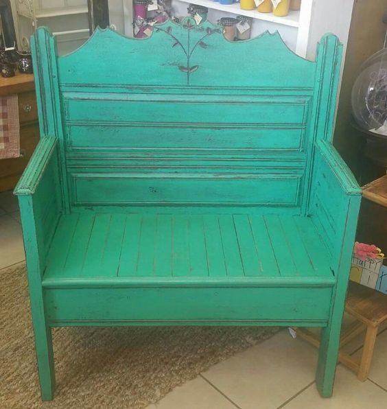 Turquoise wooden bench with slatted back and seat, displayed indoors in a shop.