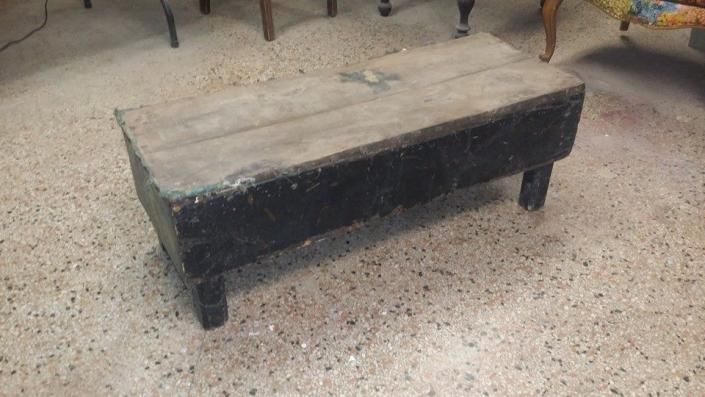 Rectangular wooden bench with black legs on a terrazzo floor.