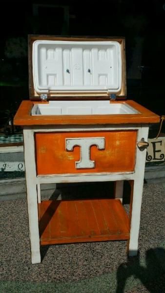 Orange-and-white wooden stand with a large white letter T on the front, holding an open white case on top.