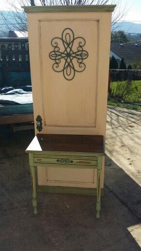 Decorative cream-colored wooden cabinet with ornate metal design, standing outdoors in sunlight
