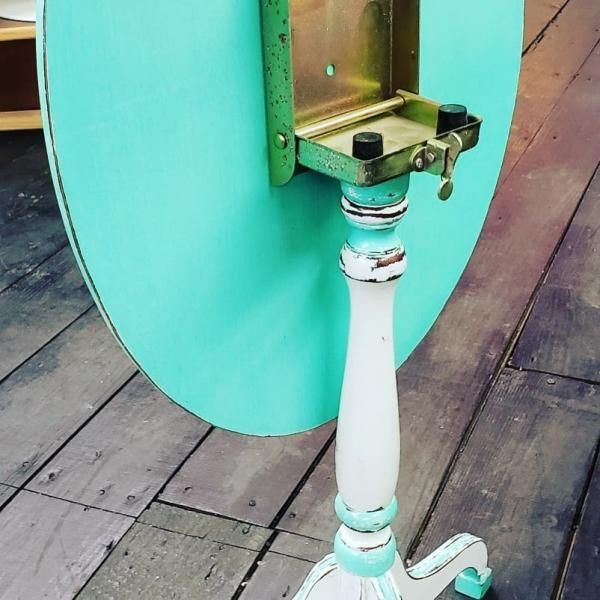 Turquoise scooter wheel and white stem on a wooden deck