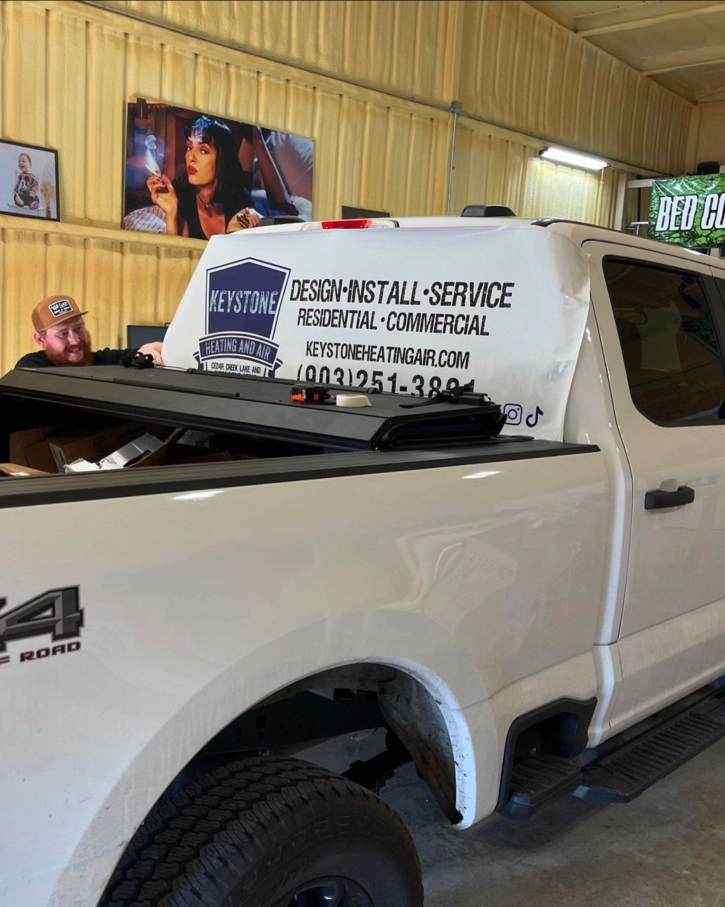 A white truck is parked in a garage with a man sitting in the back.