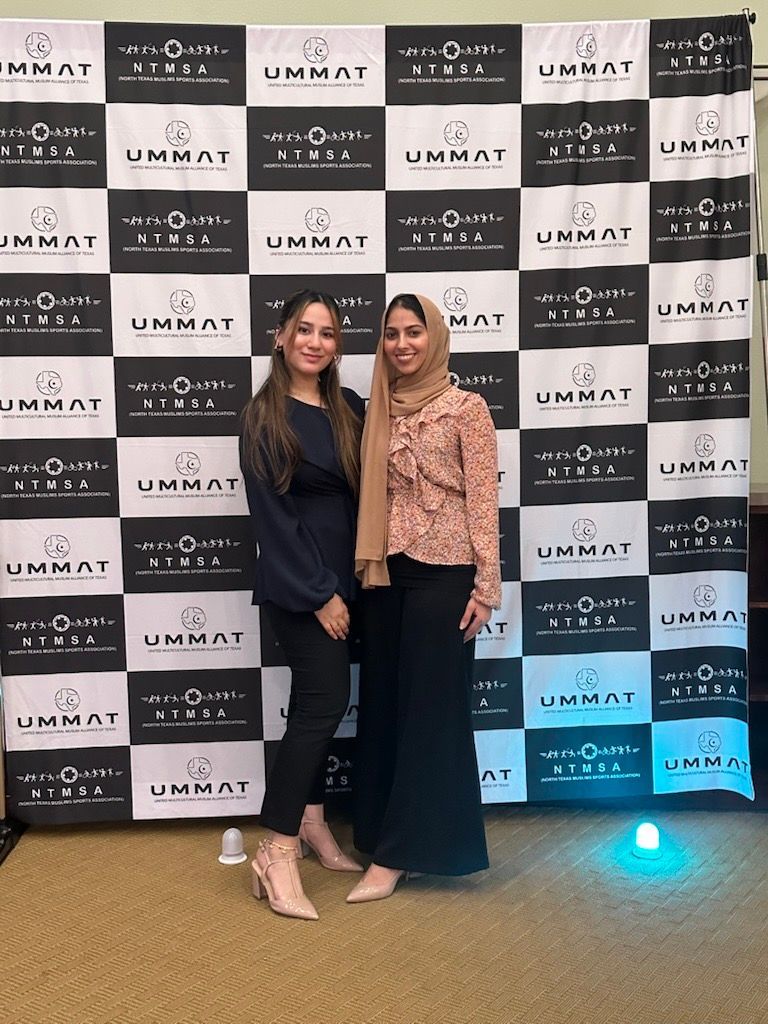 Two women pose in front of a checkered backdrop with