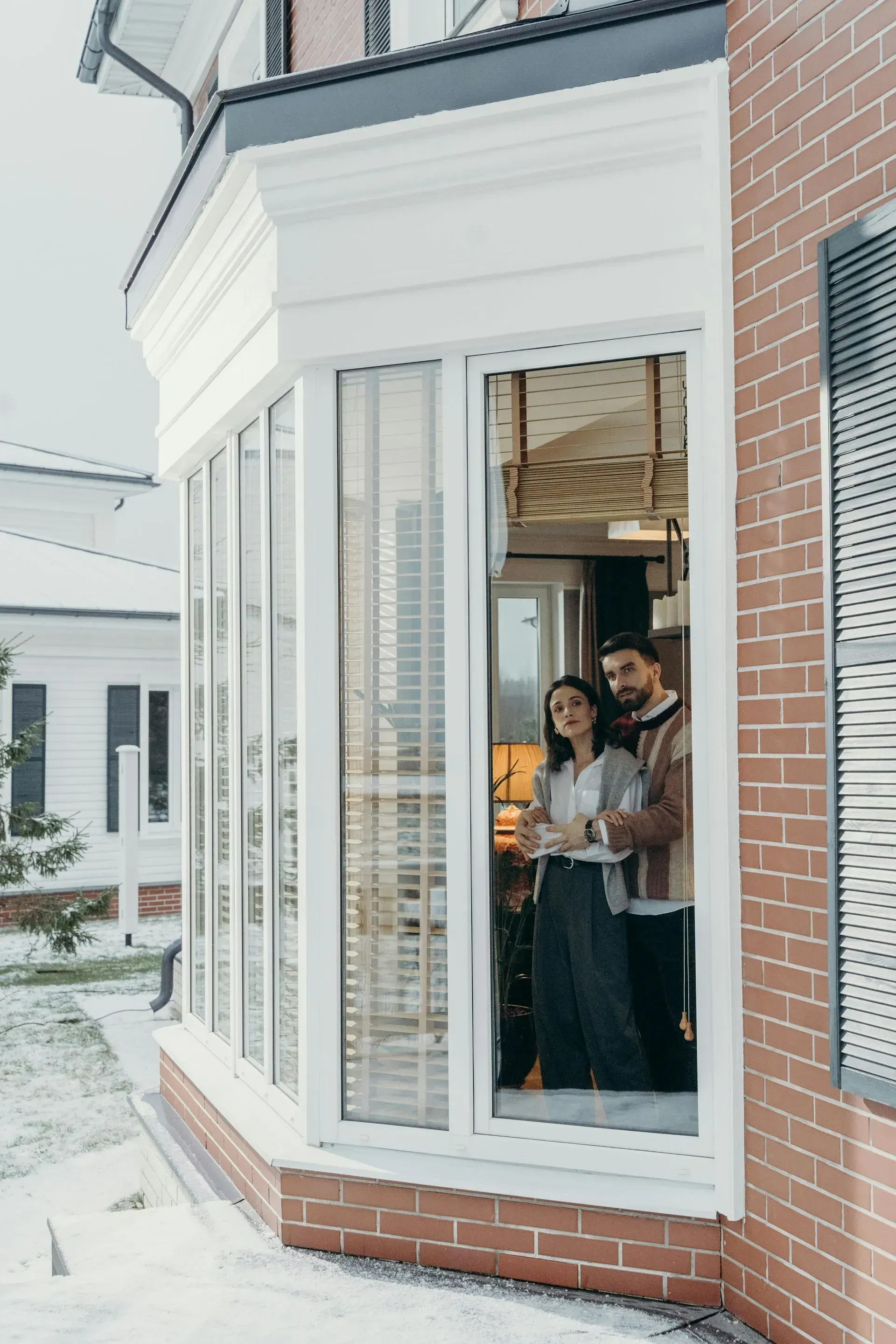 A wooden door is open and surrounded by potted plants.
