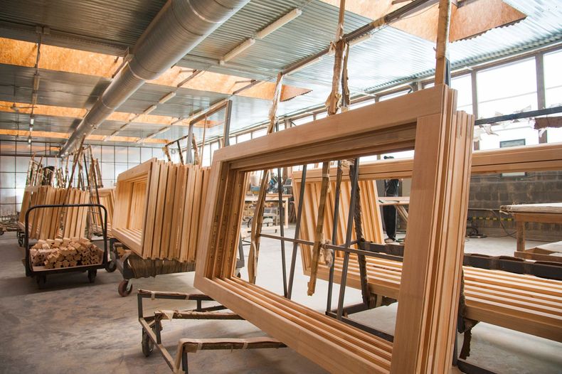 Wooden window frames in a factory, stacked and hanging to dry.