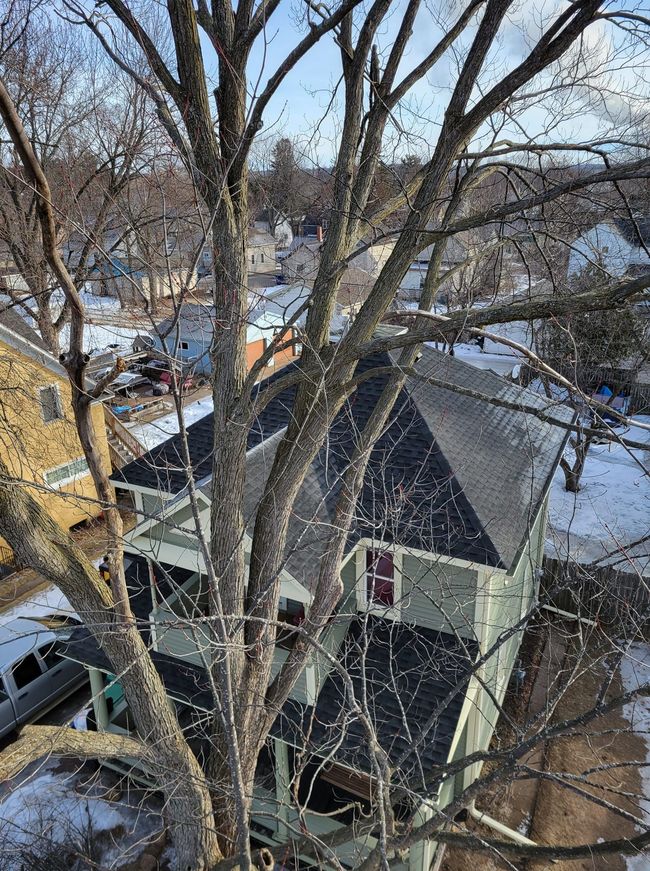 Residential tree removal near roofline in Schofield WI during winter
