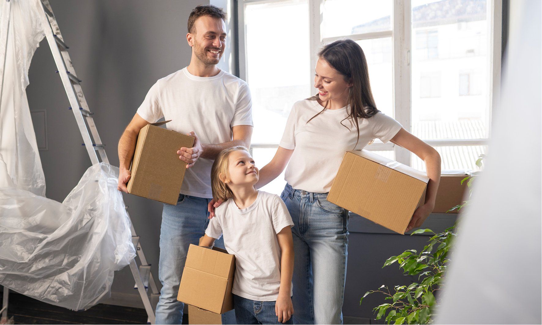 Uma família está se mudando para uma nova casa e segurando caixas de papelão.