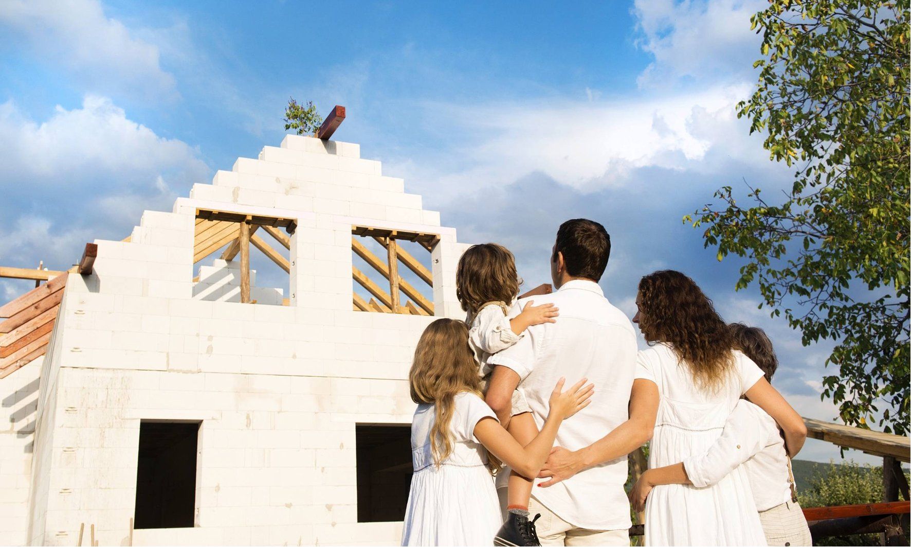 Uma família está diante de uma casa em construção.