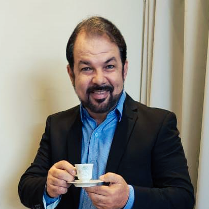 Um homem de terno está segurando uma xícara de café.
