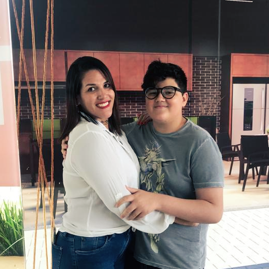 Uma mulher está abraçando um menino que usa óculos