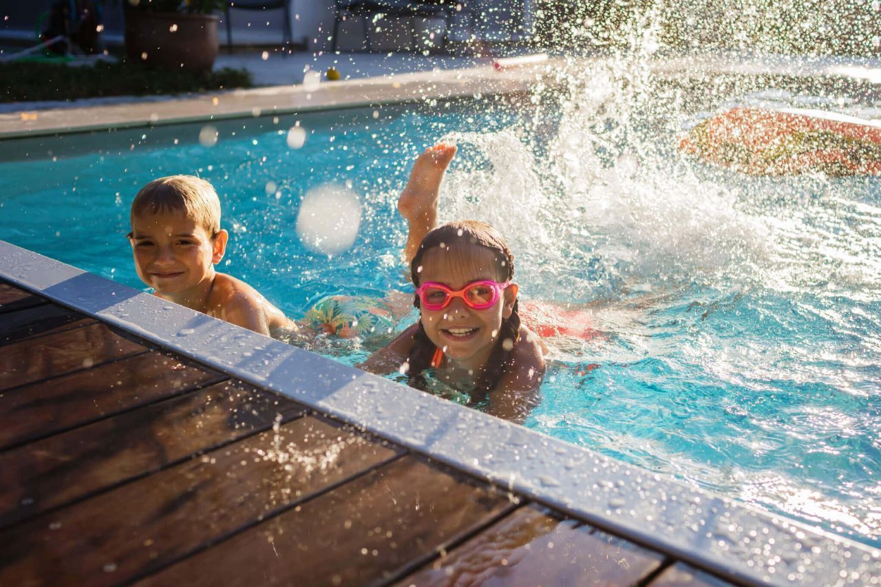 jovens-nadando-na-piscina Um menino e uma menina estão nadando em uma piscina.