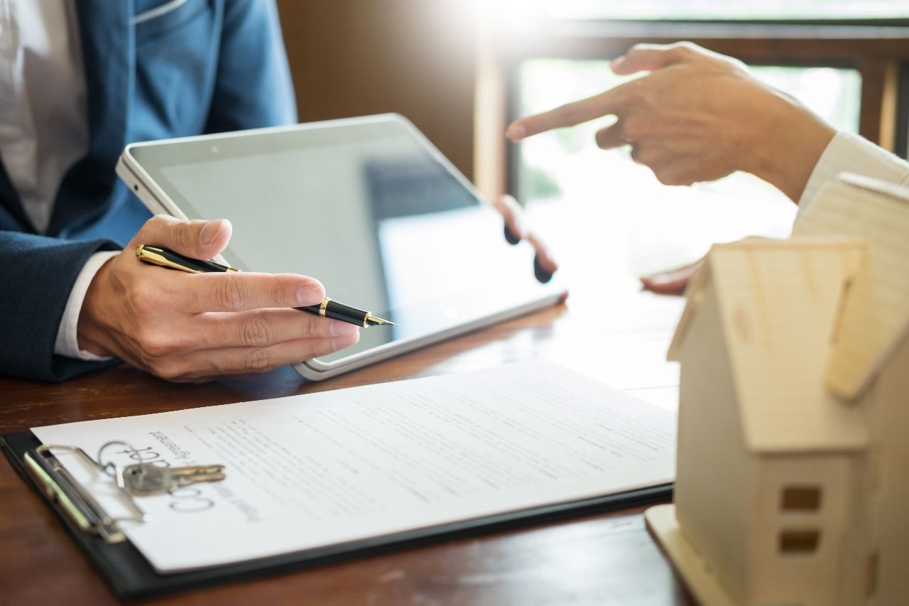 negociacao Um homem e uma mulher estão sentados à mesa olhando para um tablet.