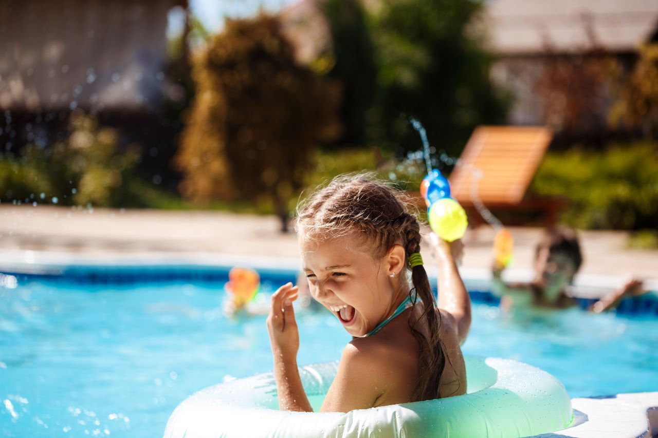 piscina-nova-alcantara Uma menina está brincando com balões de água em uma piscina.