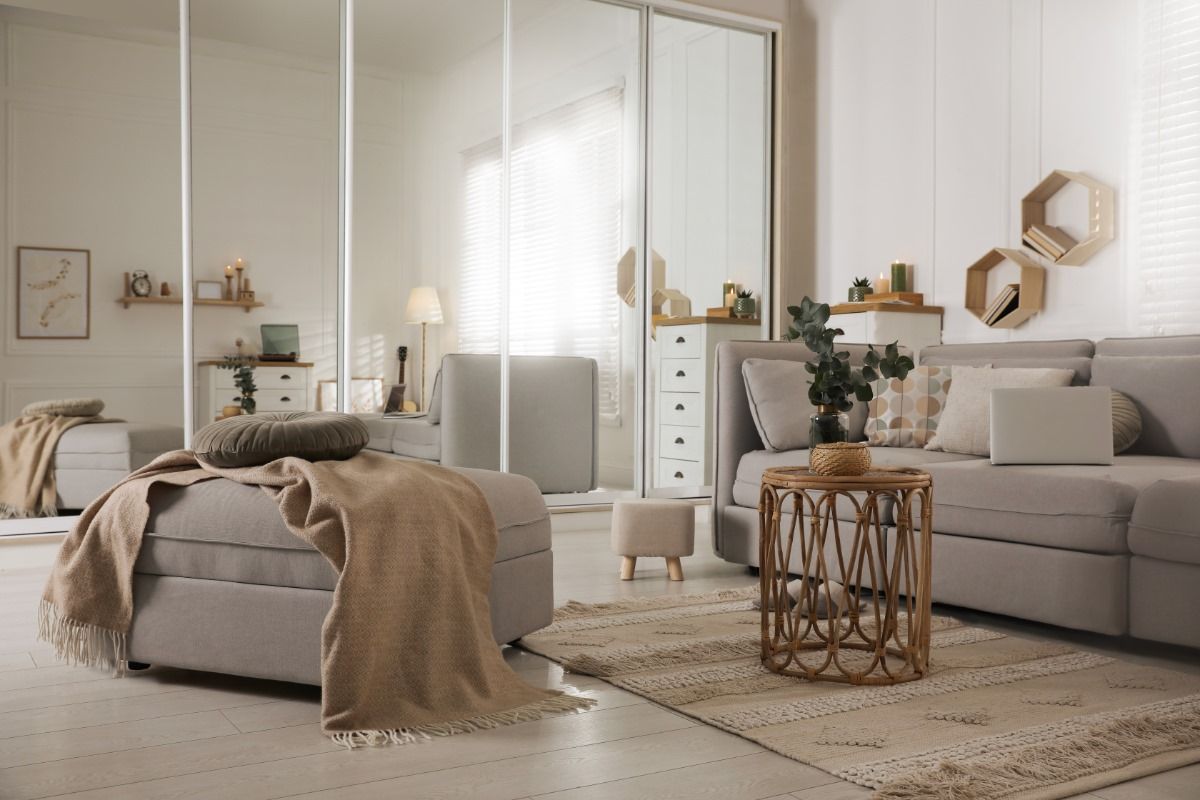 sala-tons-de-branco Uma sala com sofá, cadeira, mesa e espelhos.