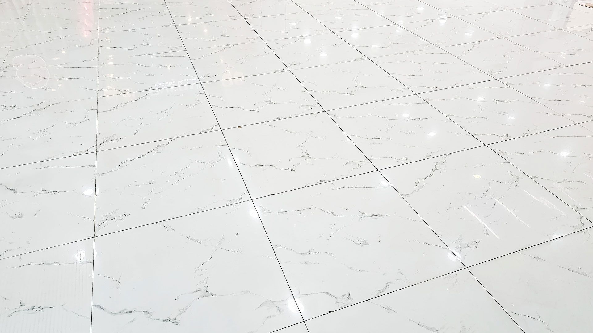 White tiled floor with faint gray marble veining and diagonal grout lines