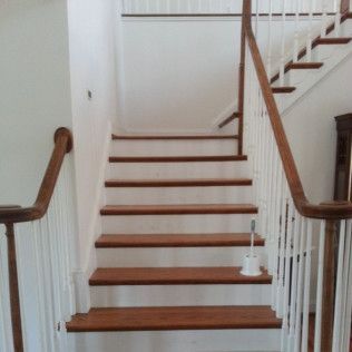 Staircase with wooden steps, white walls, and white balusters in a home interior