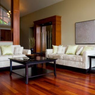 Modern living room with beige sofas, dark wood coffee table, and polished hardwood floors.