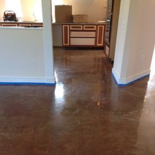 Empty room with polished brown floor, white walls, and a doorway to a small kitchen area.