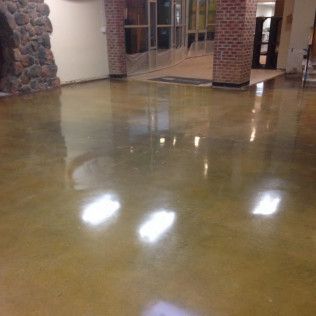 Shiny polished floor in a building lobby with brick columns and glass doors reflecting lights