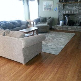 Cozy living room with sofas, armchair, coffee table, rug, and stone fireplace on hardwood floors.