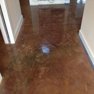 Shiny brown polished floor in a hallway with white walls and blue painter’s tape along the baseboards