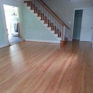Empty living room with hardwood floors, staircase, and doorways to adjacent rooms