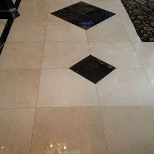 Beige tiled floor with two black diamond-shaped inlays and a shiny surface