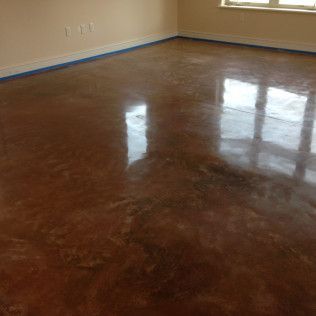 Empty room with polished brown concrete floor and beige walls reflecting light from a window.