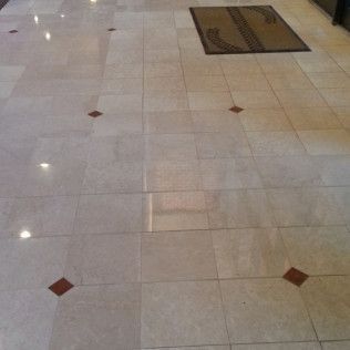 Polished beige tiled floor with small brown diamond accents and a doormat near the top edge