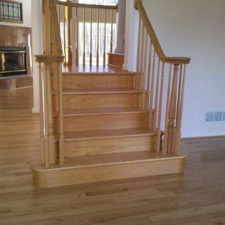 Wooden staircase with railing in a living room, beside a fireplace and hardwood floor